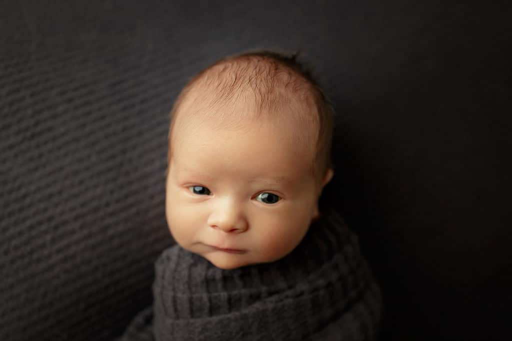 newborn boy wide awake and swaddled