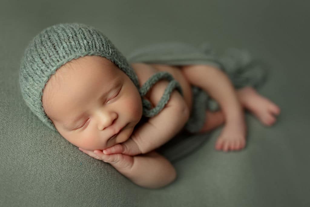 sleeping sweet baby boy in green hat on green blanket