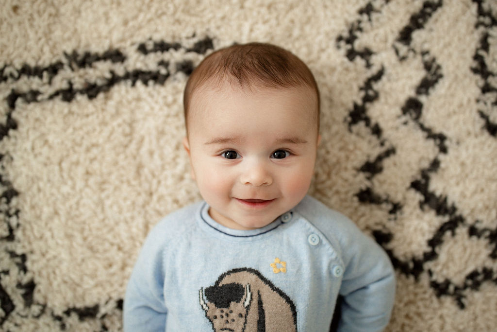 sweet four month old baby laying on a rug