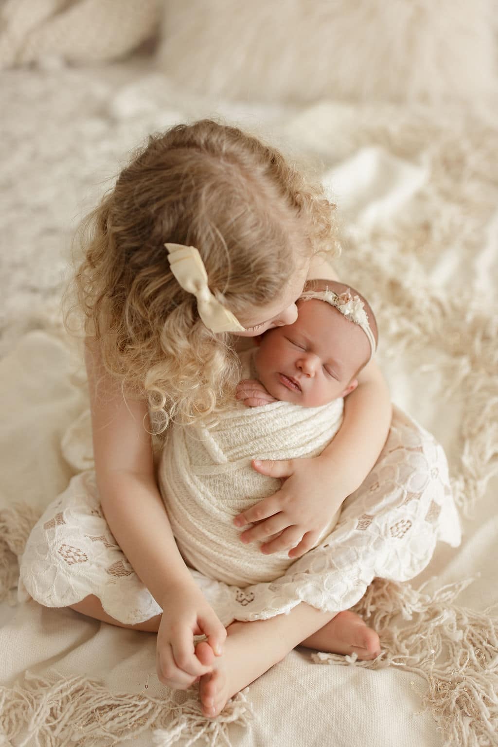 big sister kisses newborn baby sister