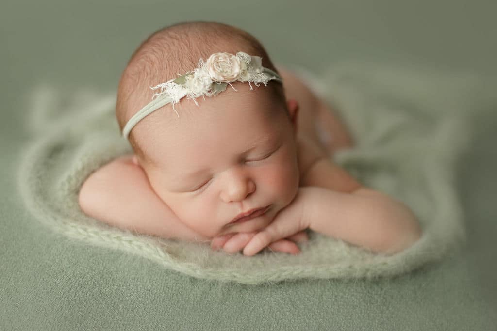 newborn girl asleep on green wrap