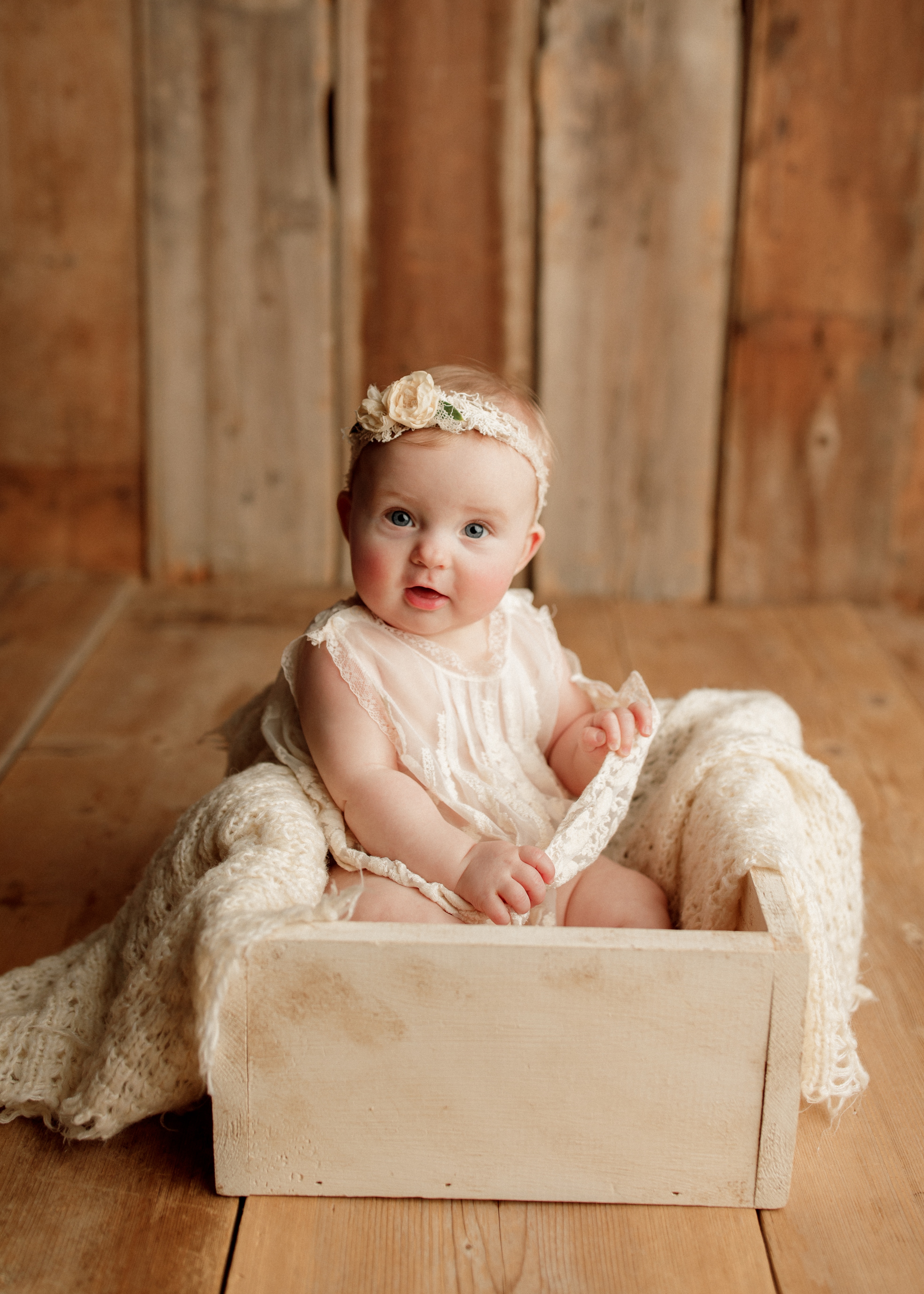 baby girl sitting in wood box at photo shoot